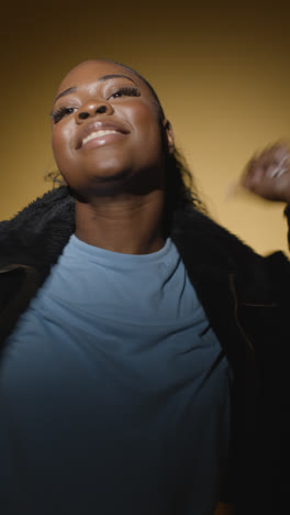 Vertical-Video-Backlit-Head-And-Shoulders-Studio-Portrait-Shot-Of-Young-Woman-Dancer-Dancing-In-Spotlight